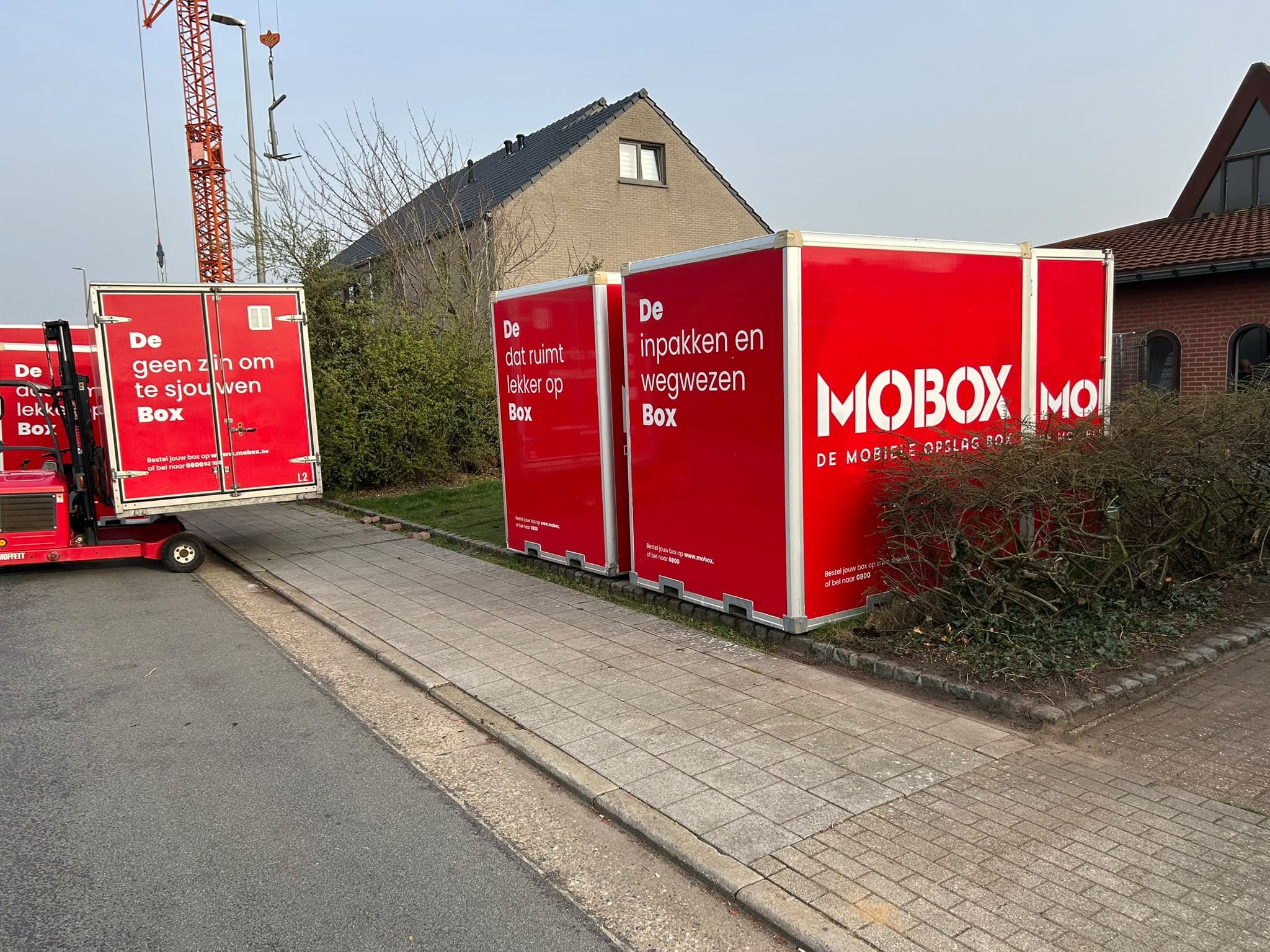 MOBOX-boxen op een oprit naast een bouwwerf met kraan